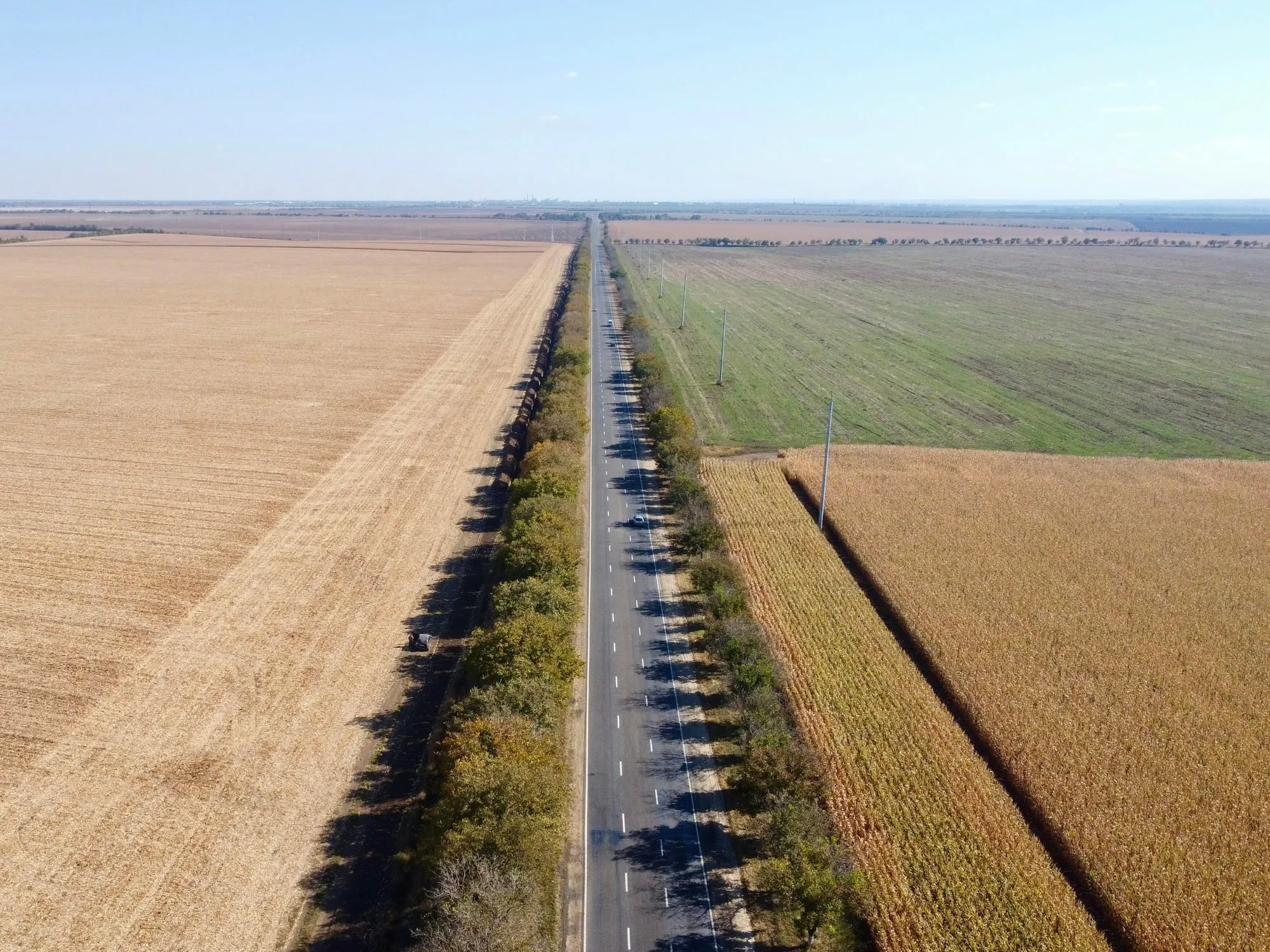 Stimmungsbild: eine schnurgerade Landstraße zieht sich aus der Luft betrachtet durch weite Felder