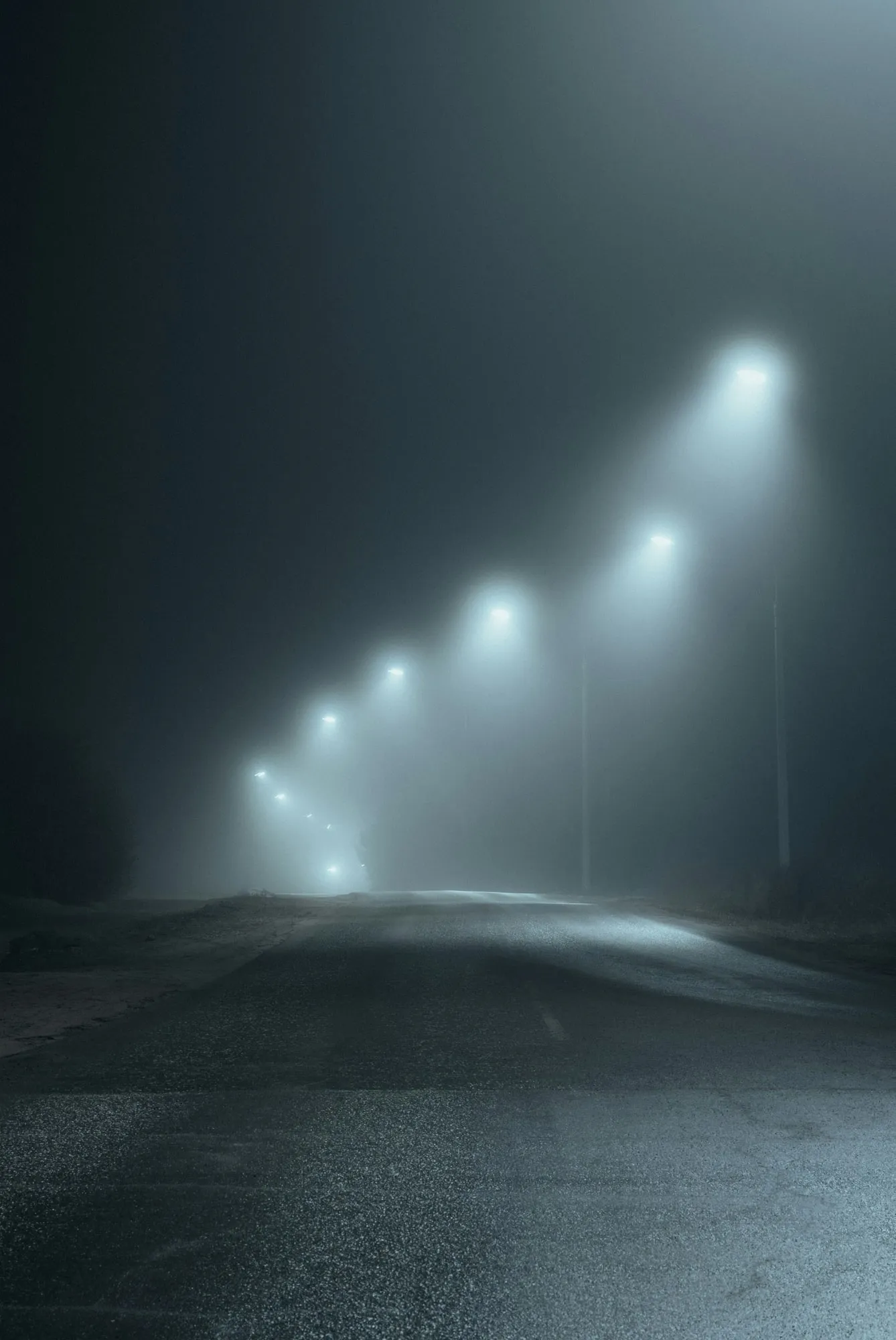 Stimmungsbild: eine leere Straße bei Nacht, nur von Laternen ausgeleuchtet